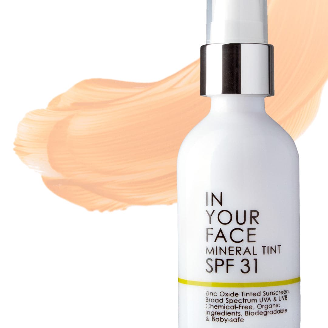 a clean image of the MINERAL TINT SPF 31 on a white background. It's a white bottle with a clear cap over a white dispenser. There is a smear of the SPF, showing it to be a light beige color. The bottle says "Zinc Oxide Tinted Sunscreen. Broad Spectrum UVA & UVB. Chemical-Free, Organic Ingredients. Biodegradable & Baby-Safe". 