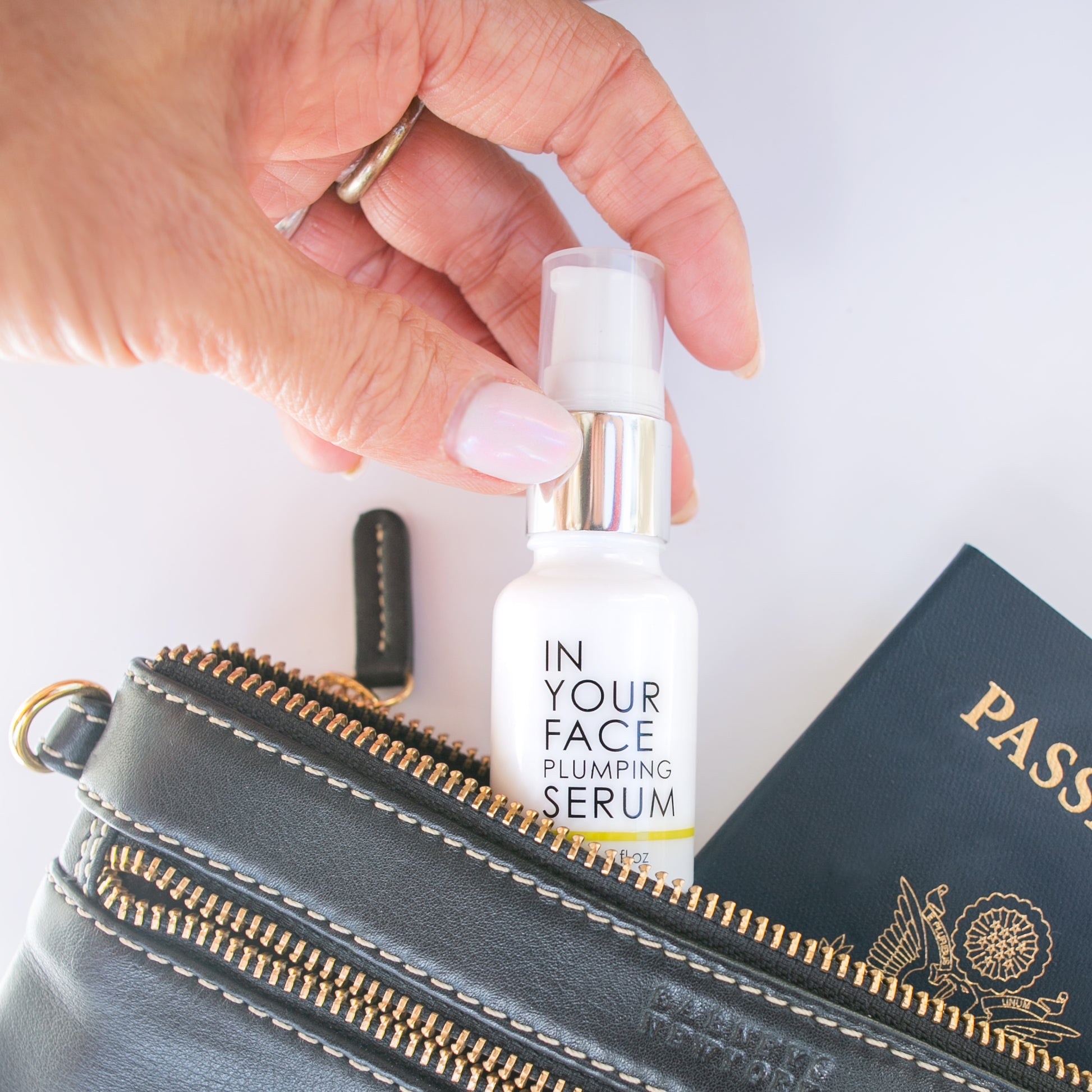 mini vit C plumping serum coming out of a purse next to passport