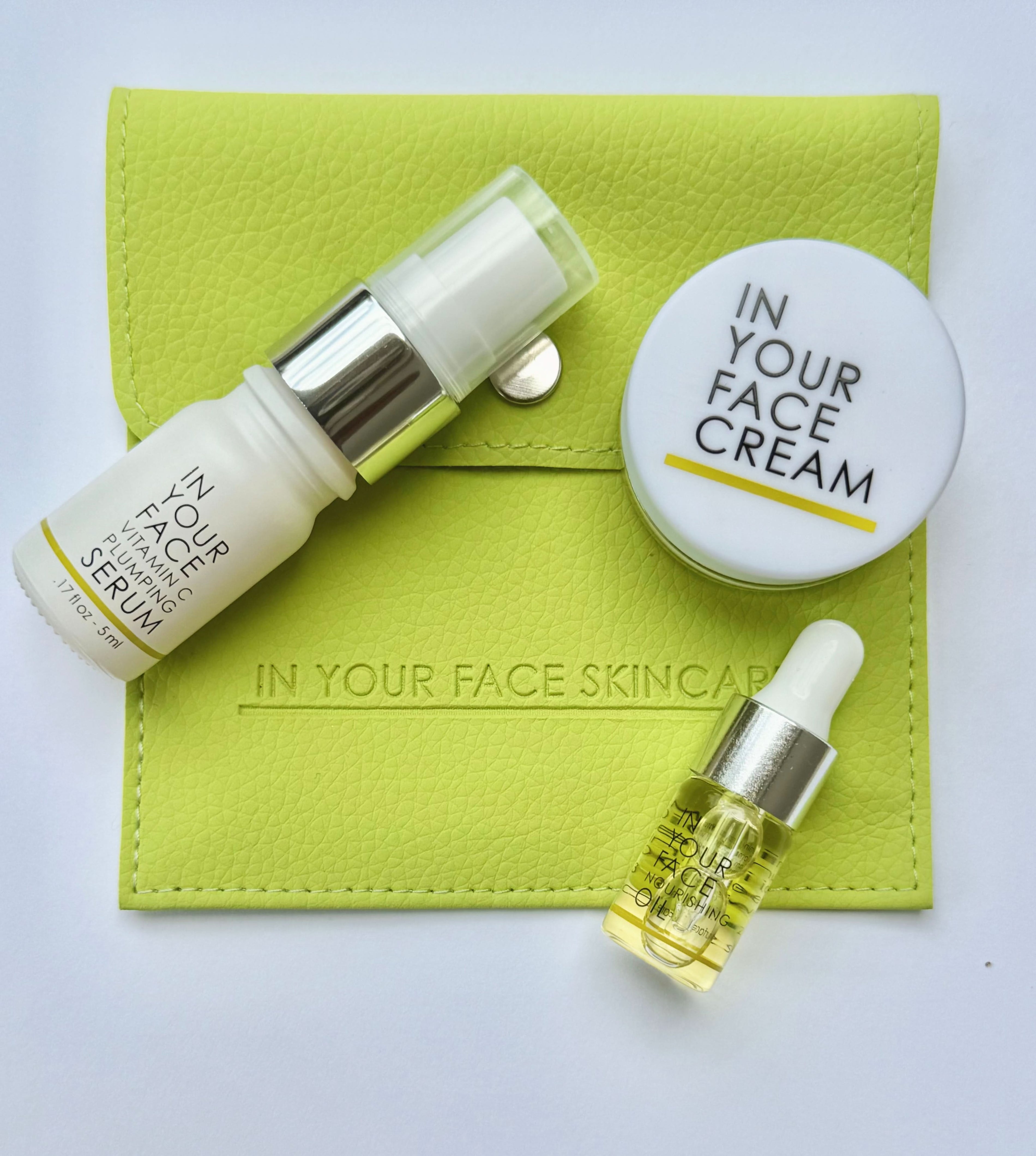 Three skincare products from IN YOUR FACE SKINCARE are arranged on a light gray background with a lime green pouch. The products include a white serum bottle, a white cream jar labeled 'IN YOUR FACE CREAM', and a small dropper oil bottle with a gold cap.
