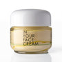 A glass jar of 'In Your Face Cream' with a white lid, containing a pale yellow cream, set against a clean white background with a soft reflection.