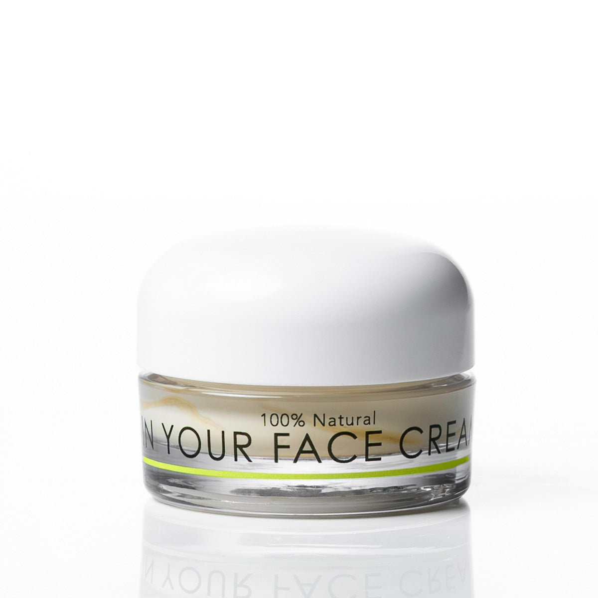 A small clear jar of face cream with a white lid and a label reading '100% Natural' and 'IN YOUR FACE CREAM', shown on a clean white background with a faint reflection below.