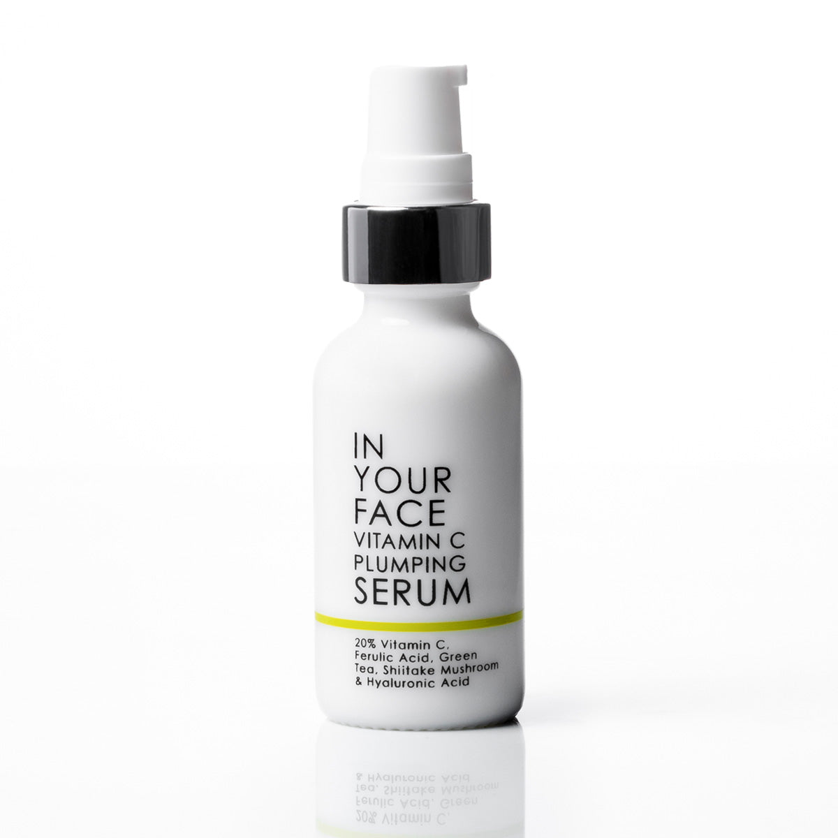 A white pump bottle of 'In Your Face Vitamin C Plumping Serum' with a black collar and a thin yellow accent line on the label, set against a clean white background with a soft reflection below.