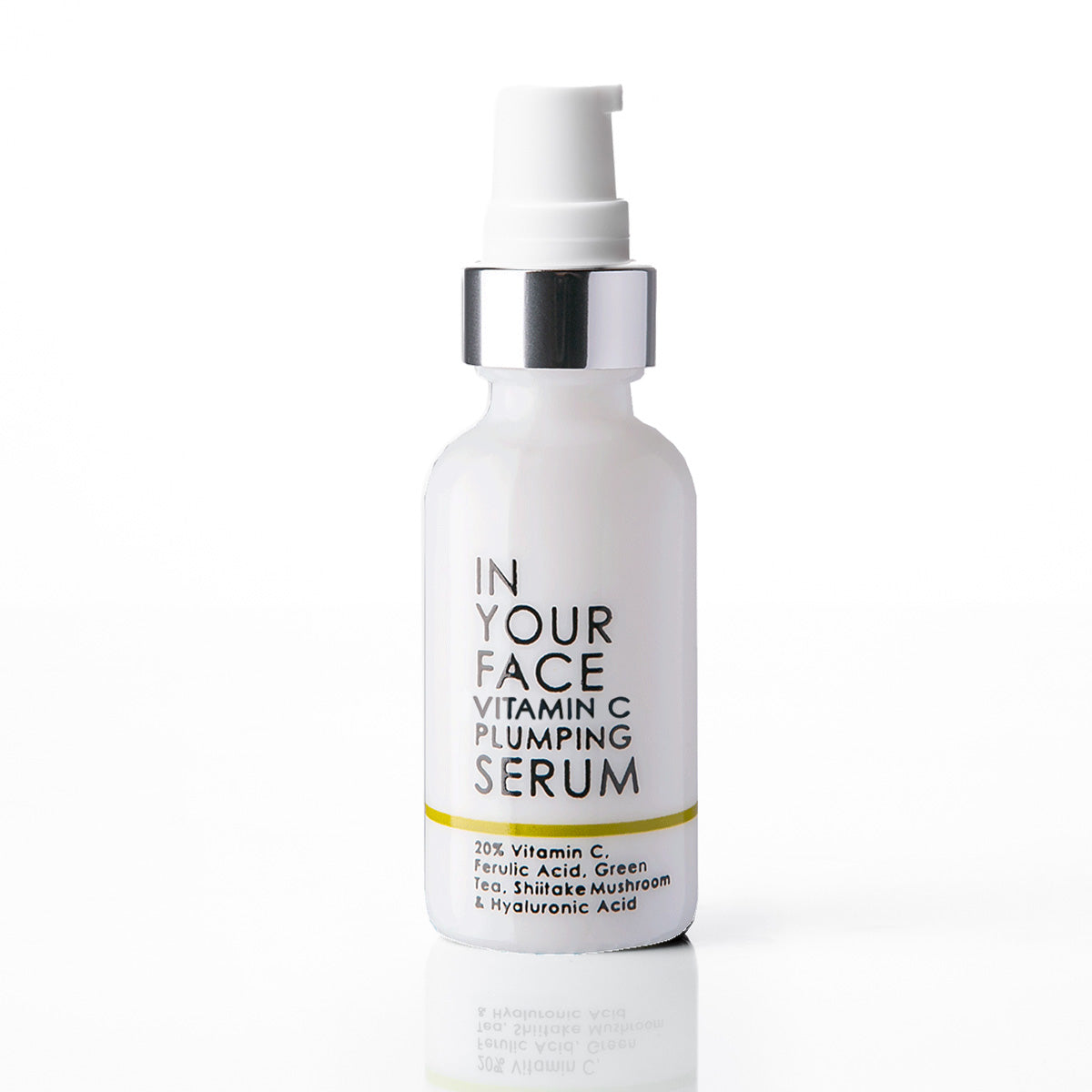 A white glass bottle of IN YOUR FACE Vitamin C Plumping Serum with a silver pump collar and black text, set against a clean white background with a soft reflection below.