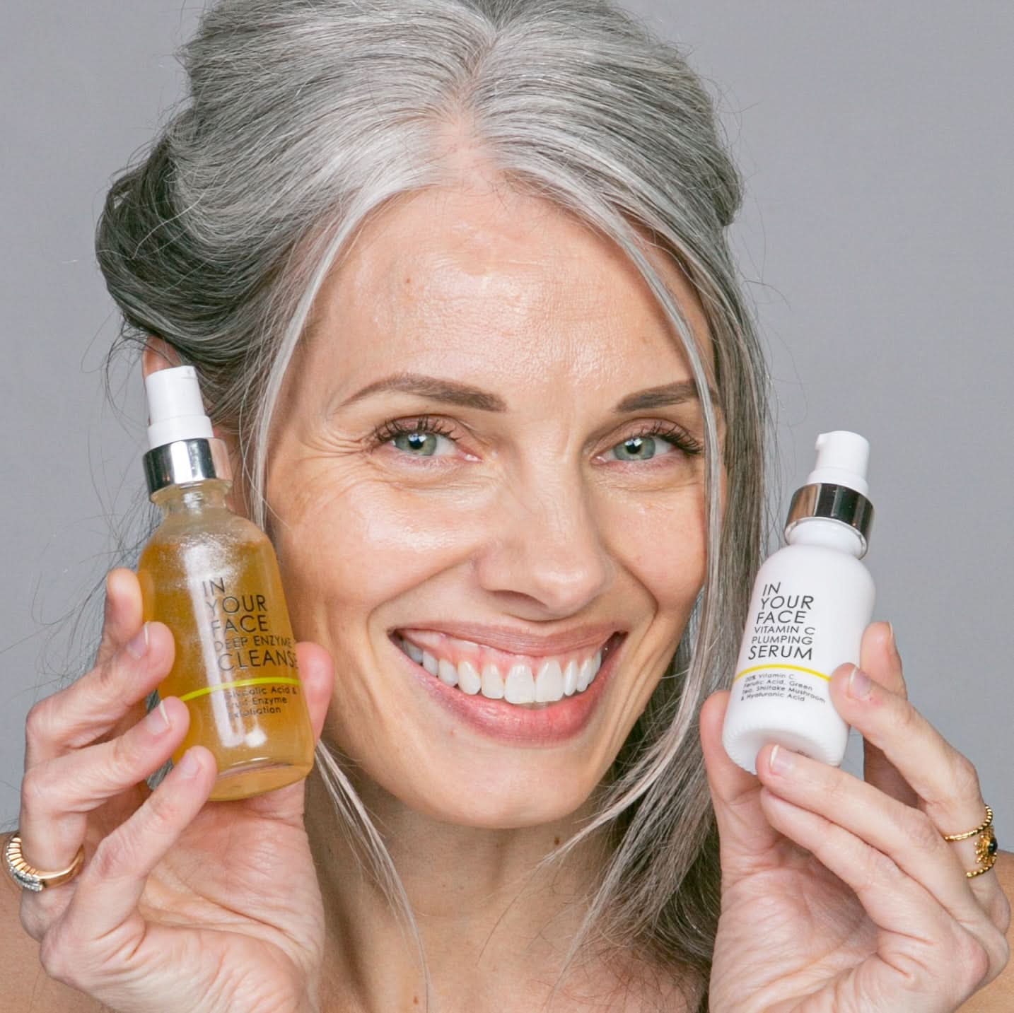 BRIGHTENING DUO - woman holding DEEP ENZYME CLEANSE and VITAMIN C PLUMPING SERUM