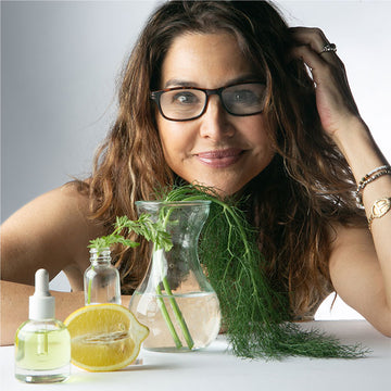 an image of DENICE DUFF in front of glass jars of oil and botanicals
