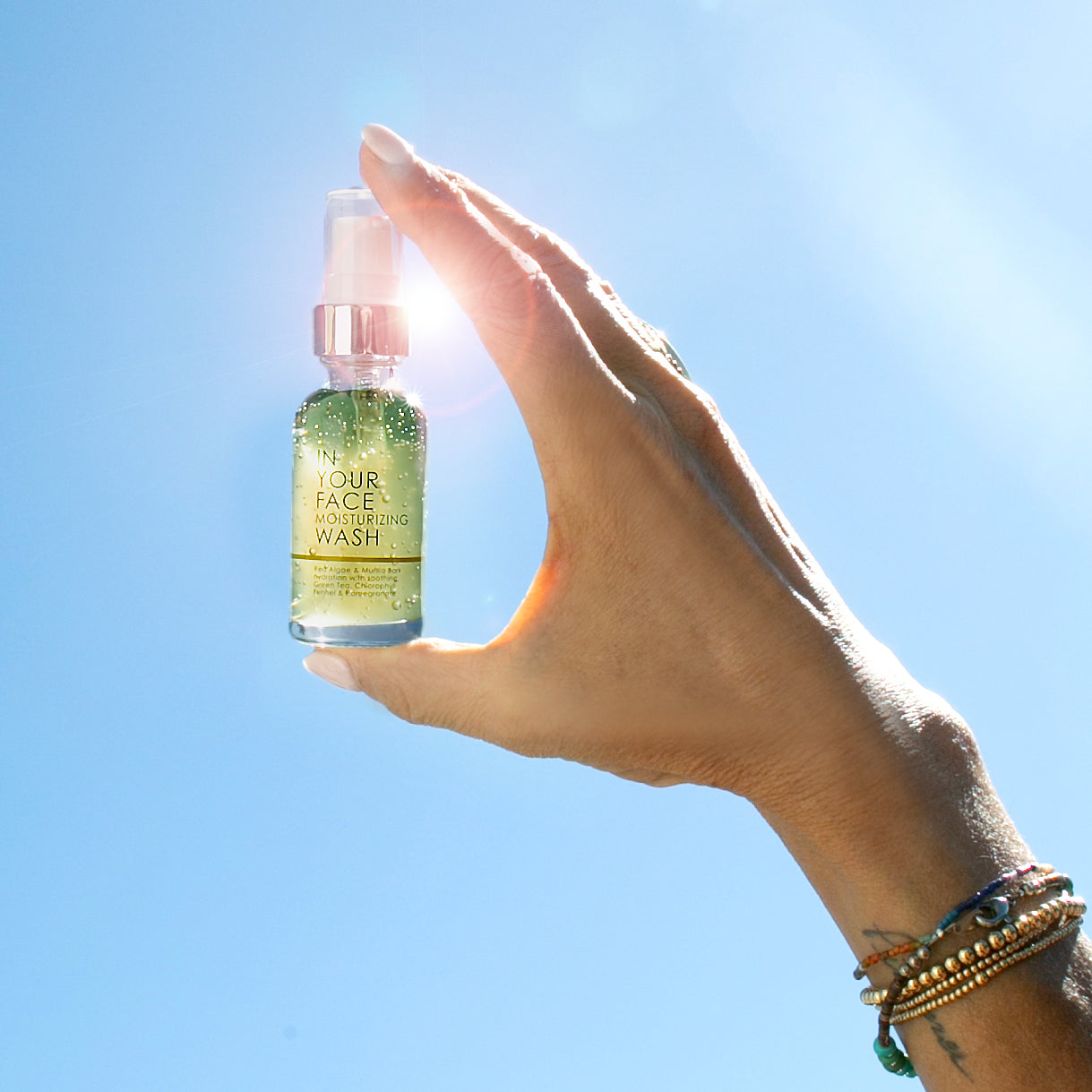 moisturizing wash mini held in blue sky with light flare