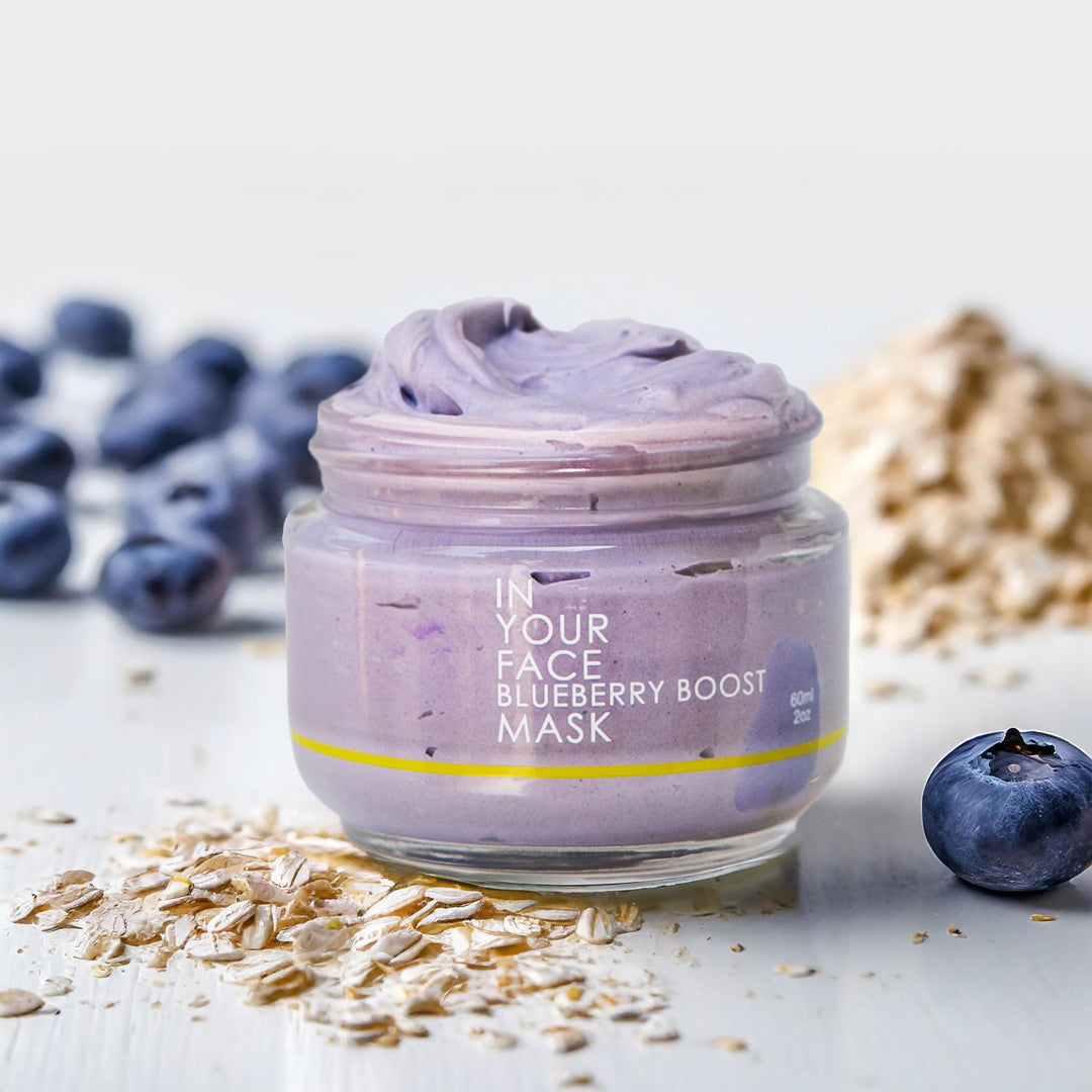 a photo of the BLUEBERRY BOOST MASK open showing the lovely whipped texture, and some oats and blueberries next to the jar.