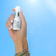 mini vitamin c plumping serum held in the sky