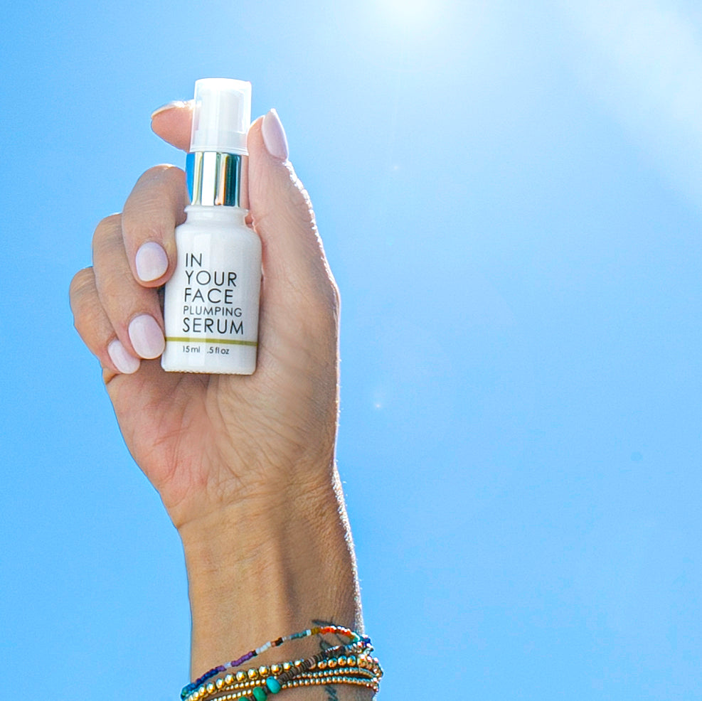 mini vitamin c plumping serum held in the sky