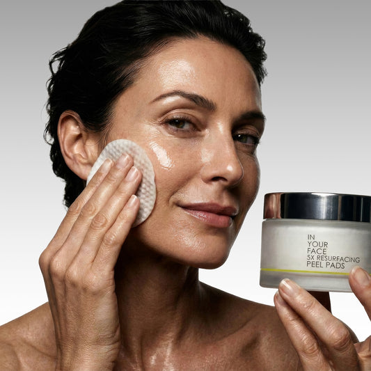 woman wiping face with peel pad