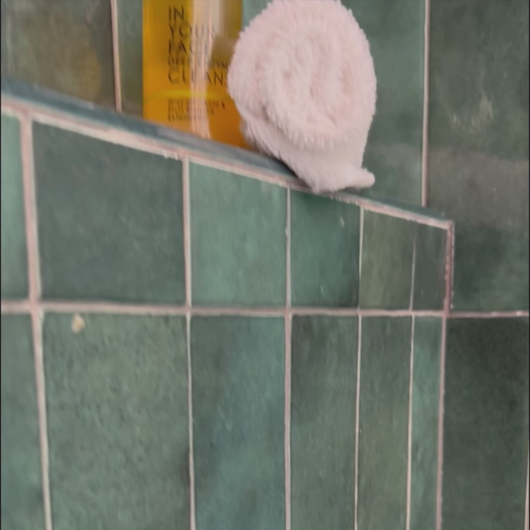 A video showing a woman in the shower squirting a few pumps into her hand of the DEEP ENZYME CLEANSE and rubbing it into her face. Afterwards she is seen rubbing her face with a dry towel.