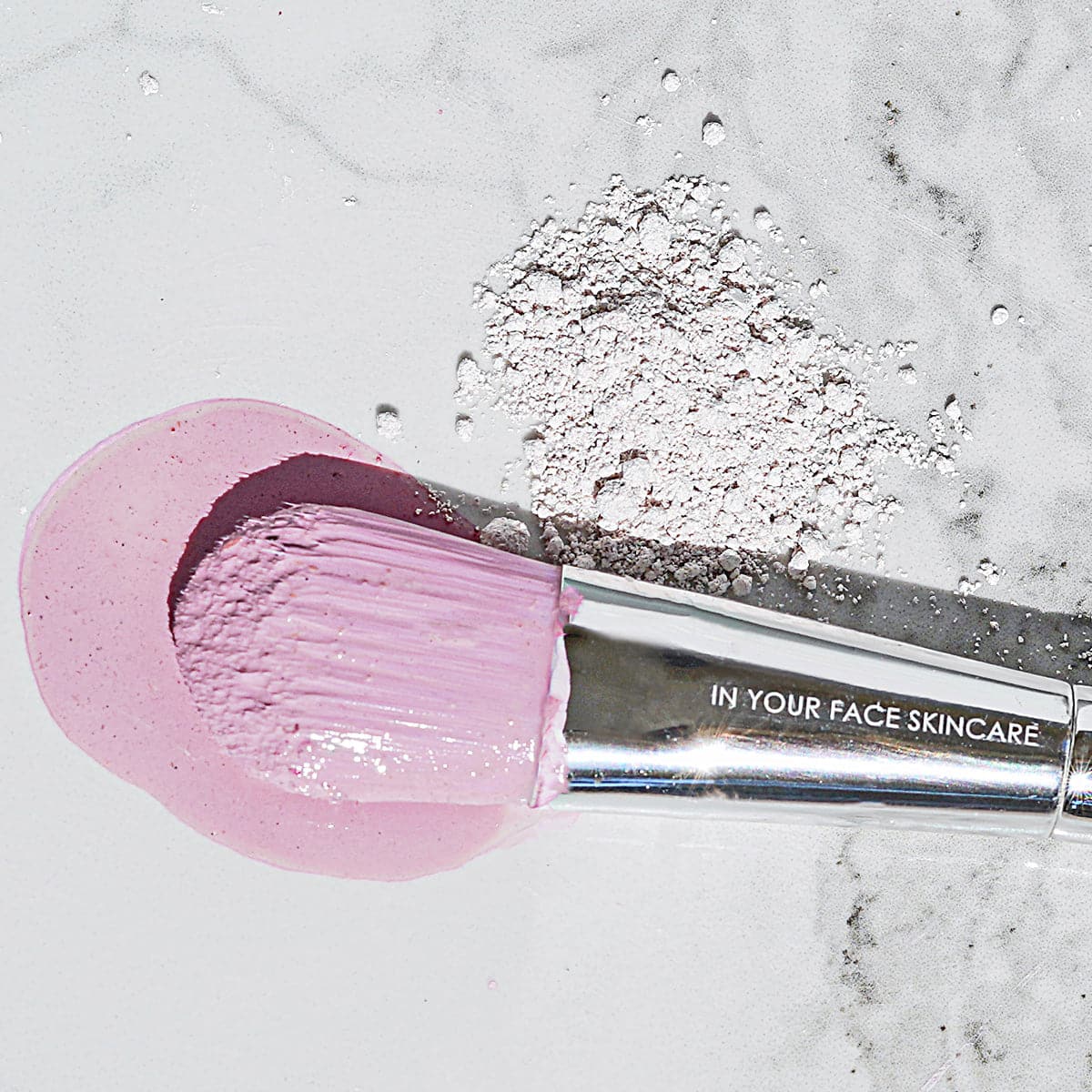 A photo of the IN YOUR FACE MASK BRUSH with some of the pink mask on it and some of the mask (not activated by water) underneath it.