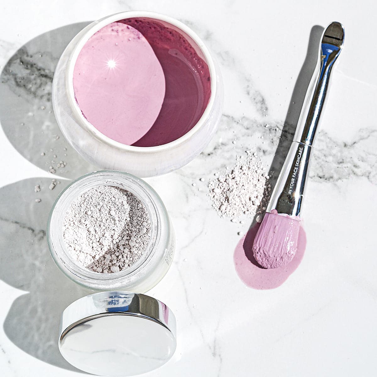 A flat lay of the RADIANT DETOX MASK open with the BOWL and MASK BRUSH next to it, inside the bowl showing a pink semi-thick liquid mask.