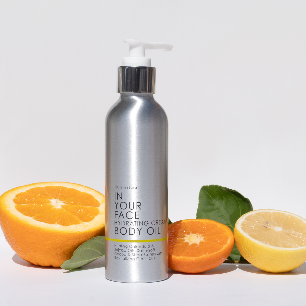 A photo of the BODY OIL standing up surrounded by a few oranges.